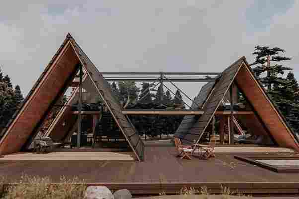 This architectural design joins two A-frame cabins together by a glass sky bridge!